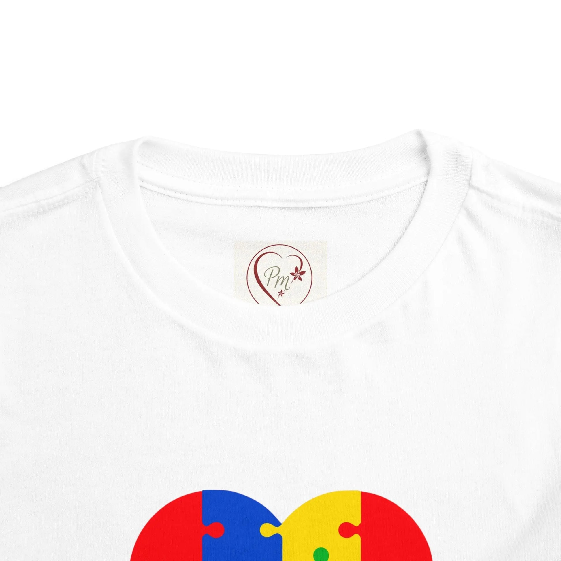 White t-shirt with a colorful puzzle heart design with a PM_Creations_25_Logo on a white background