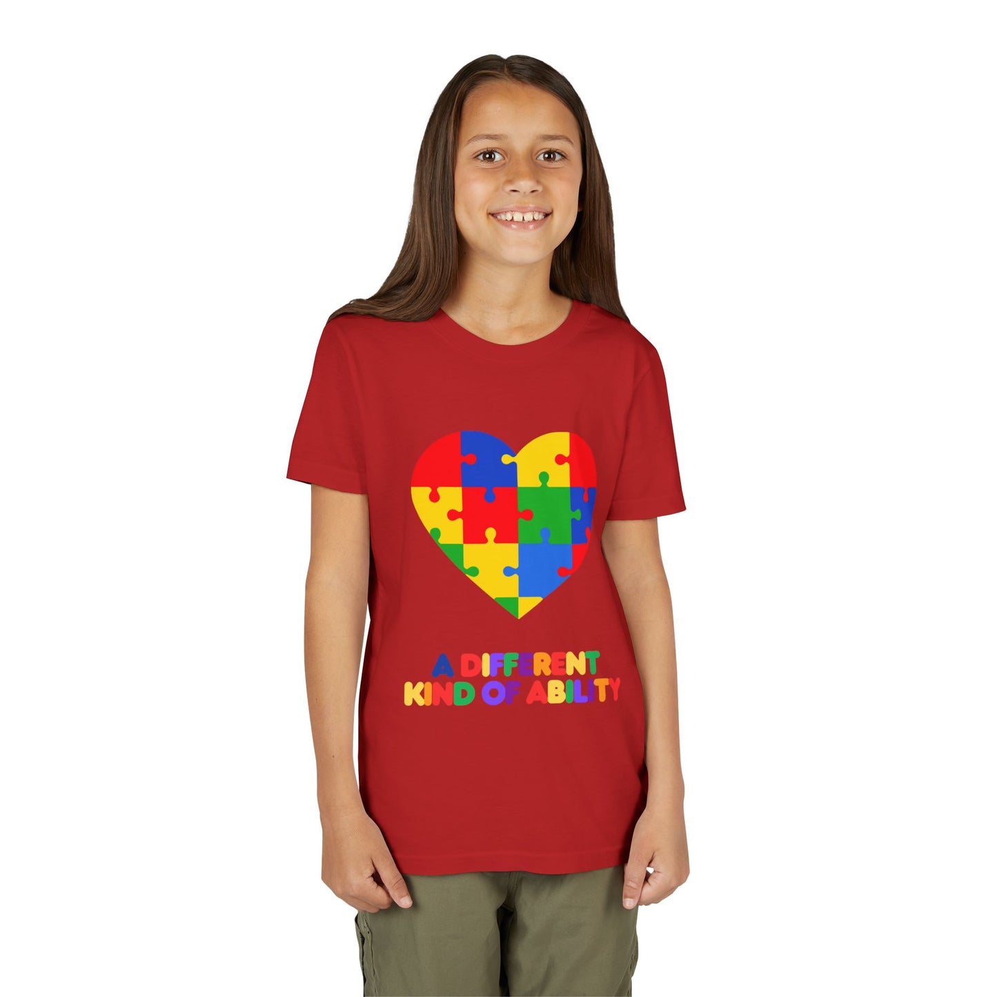 Young girl wearing an Autism Awareness Shirt. Celebrate every unique mind with this "A Different Kind of Ability" autism awareness youth tee. A puzzle heart design that spreads acceptance, love, and neurodiversity, Heather Red