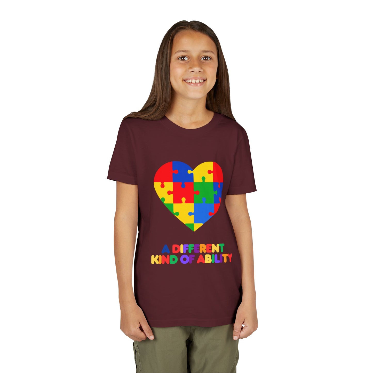 Young girl wearing an Autism Awareness Shirt. Celebrate every unique mind with this "A Different Kind of Ability" autism awareness youth tee. A puzzle heart design that spreads acceptance, love, and neurodiversity, Maroon