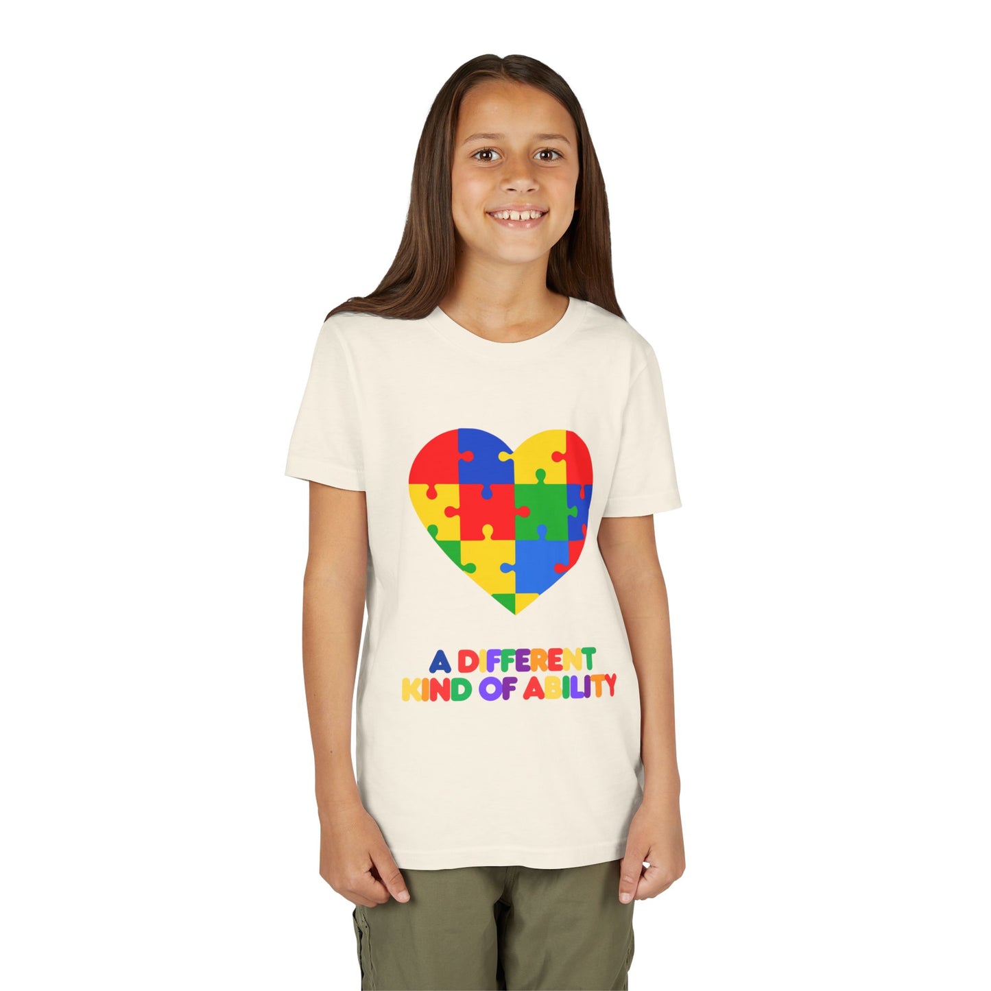 Young girl wearing an Autism Awareness Shirt. Celebrate every unique mind with this "A Different Kind of Ability" autism awareness youth tee. A puzzle heart design that spreads acceptance, love, and neurodiversity, Natural