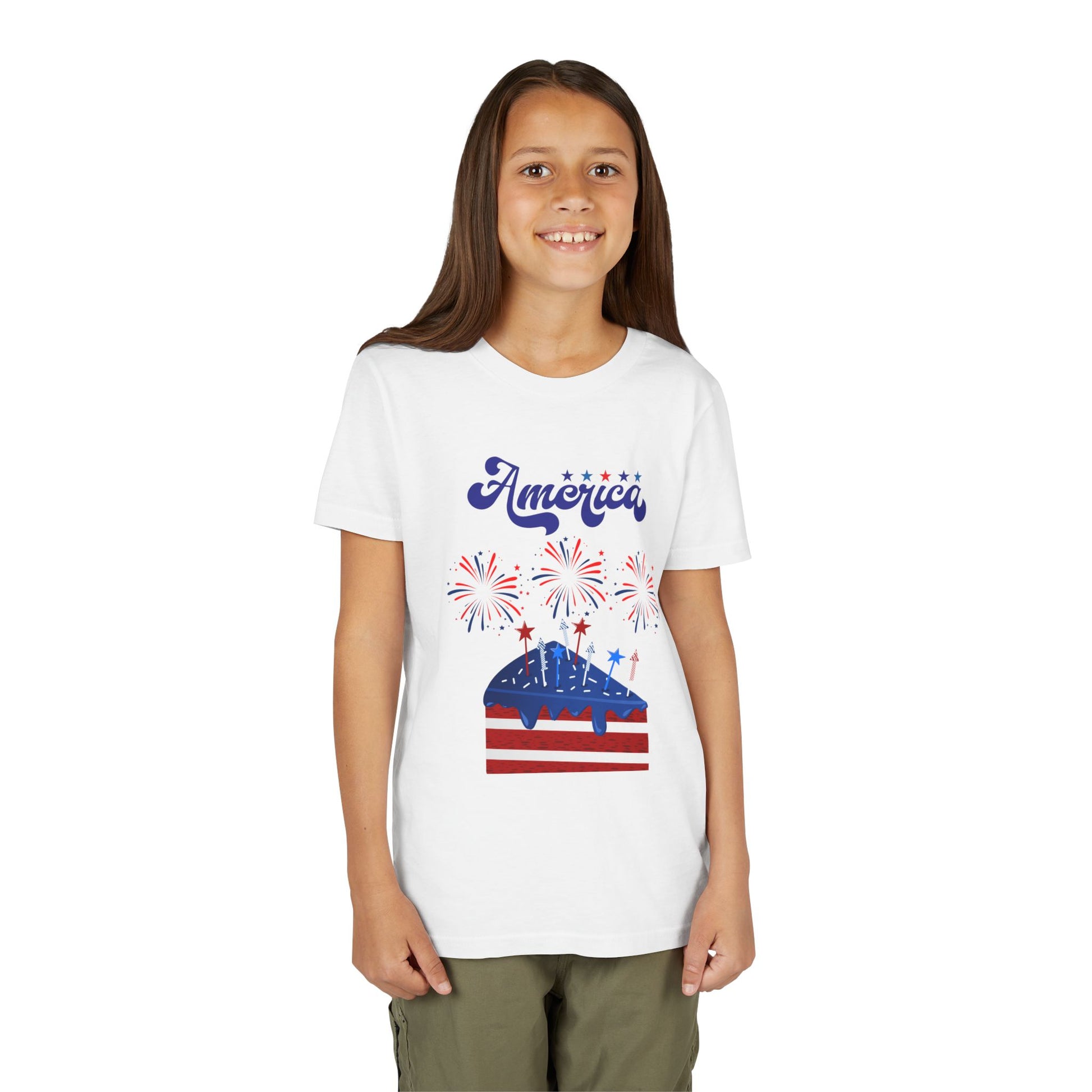 Girl wearing a White t-shirt with 'America' and a graphic design on a white background. Celebrate the 4th of July in style! This patriotic America fireworks youth tee is perfect for kids who love Independence Day festivities and summer fun.
