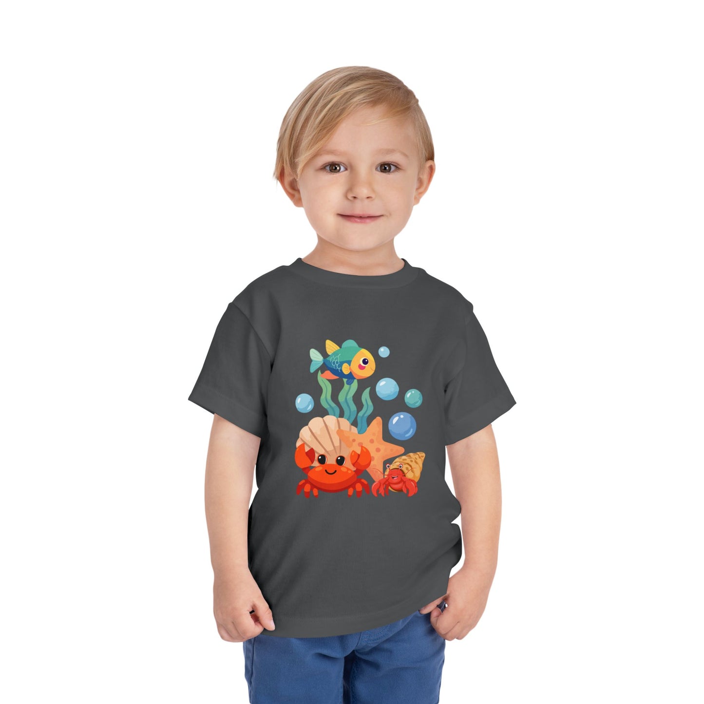 Child wearing an Asphalt t-shirt with a colorful underwater-themed graphic on a white background. Playful toddler tee with a crab, fish & shell design. Soft, breathable cotton with tear-away label. Sizes 2T–5T. Perfect for beach days & summer play!