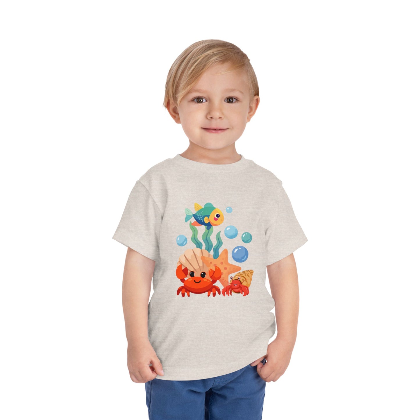 Child wearing a t-shirt with an underwater-themed design on a white background. Playful toddler tee with a crab, fish & shell design. Soft, breathable cotton with tear-away label. Sizes 2T–5T. Perfect for beach days & summer play! Heather Dust