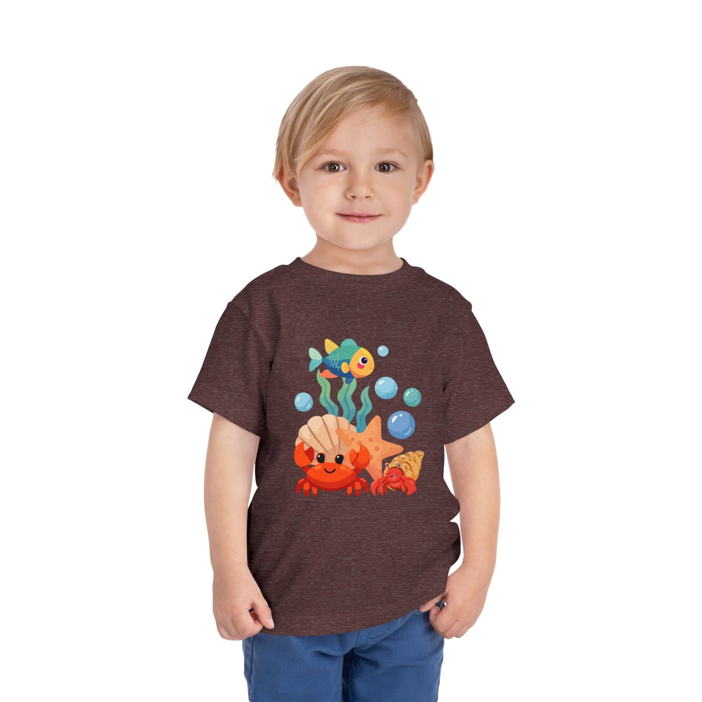 Child wearing a Heather Maroon t-shirt with a colorful graphic design on a white background. Playful toddler tee with a crab, fish & shell design. Soft, breathable cotton with tear-away label. Sizes 2T–5T. Perfect for beach days & summer play! 