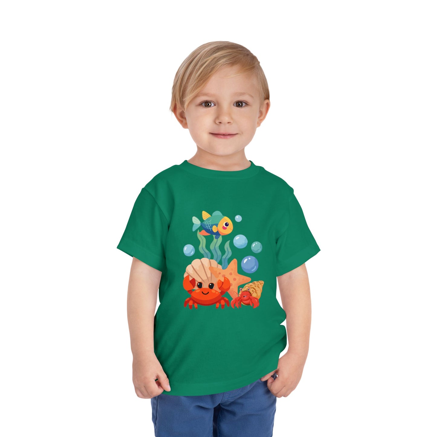 Child wearing a Kelly Green t-shirt with a cartoon design of a goldfish and clownfish. Playful toddler tee with a crab, fish & shell design. Soft, breathable cotton with tear-away label. Sizes 2T–5T. Perfect for beach days & summer play!