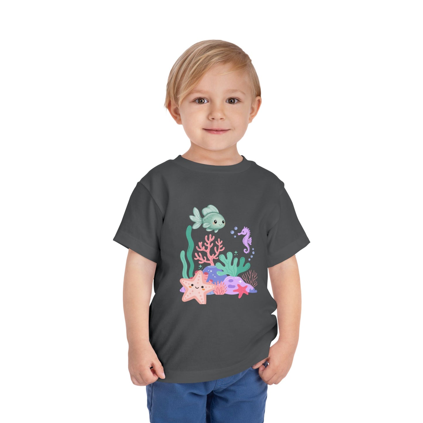 Child wearing a soft, breathable toddler tee featuring pastel sea creatures — fish, seahorse & starfish. Tear-away label, lightweight fabric. Sizes 2T–5T. Shop now! Asphalt