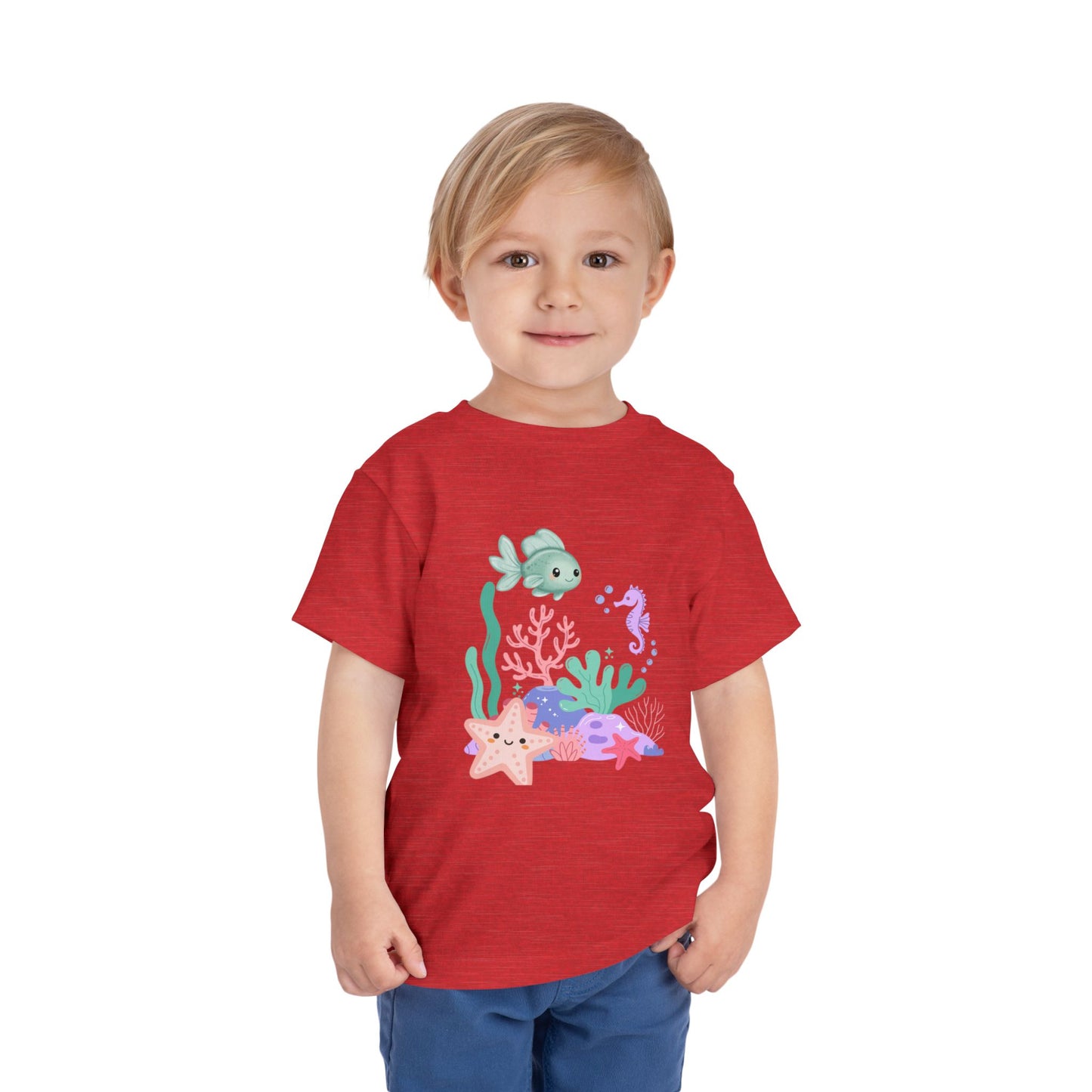 Child wearing a soft, breathable toddler tee featuring pastel sea creatures — fish, seahorse & starfish. Tear-away label, lightweight fabric. Sizes 2T–5T. Shop now! Heather Red