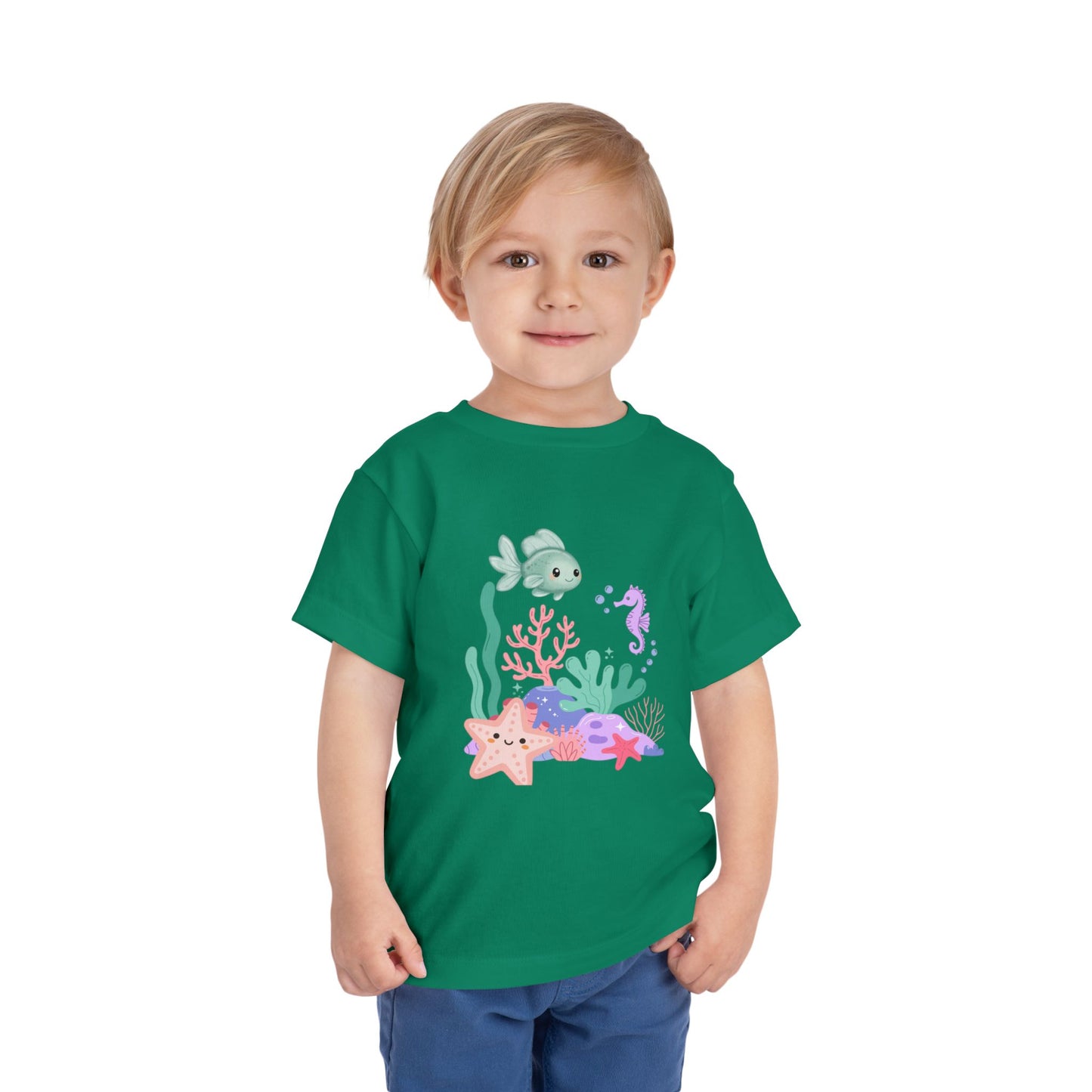 Child wearing a soft, breathable toddler tee featuring pastel sea creatures — fish, seahorse & starfish. Tear-away label, lightweight fabric. Sizes 2T–5T. Shop now! Kelly Green