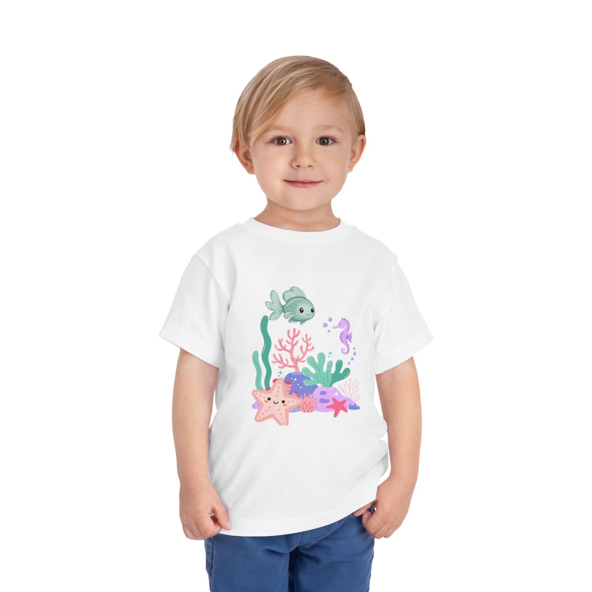 Child wearing a soft, breathable toddler tee featuring pastel sea creatures — fish, seahorse & starfish. Tear-away label, lightweight fabric. Sizes 2T–5T. Shop now! White