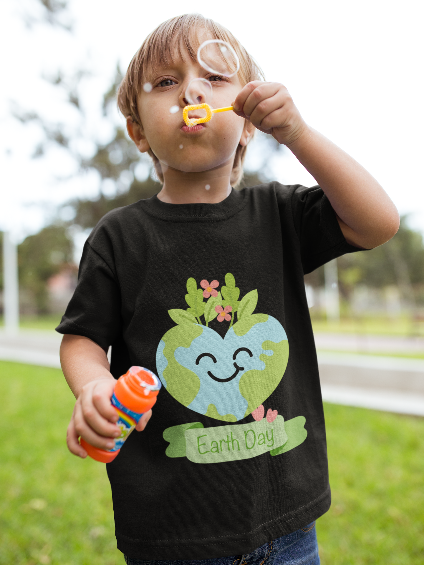 Toddler wearing Earth Day tee with smiling planet crowned with leaves and flowers in Black