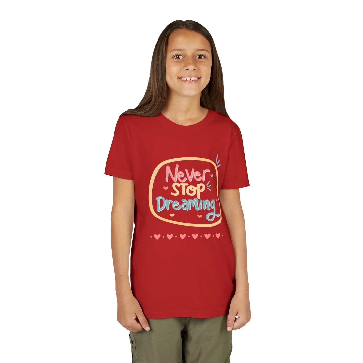 Youth wearing this encouraging youth tee with "Never Stop Dreaming" message. Soft cotton, perfect for school, everyday wear, and inspiring creativity. Motivational kids' clothing. Red