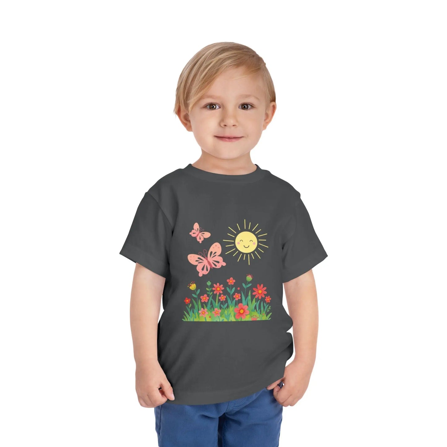Toddler wearing a cheerful toddler tee with smiling sun, butterflies, and wildflowers. Soft cotton, perfect for spring, playdates, and outdoor adventures. Bright kids' clothing. Asphalt