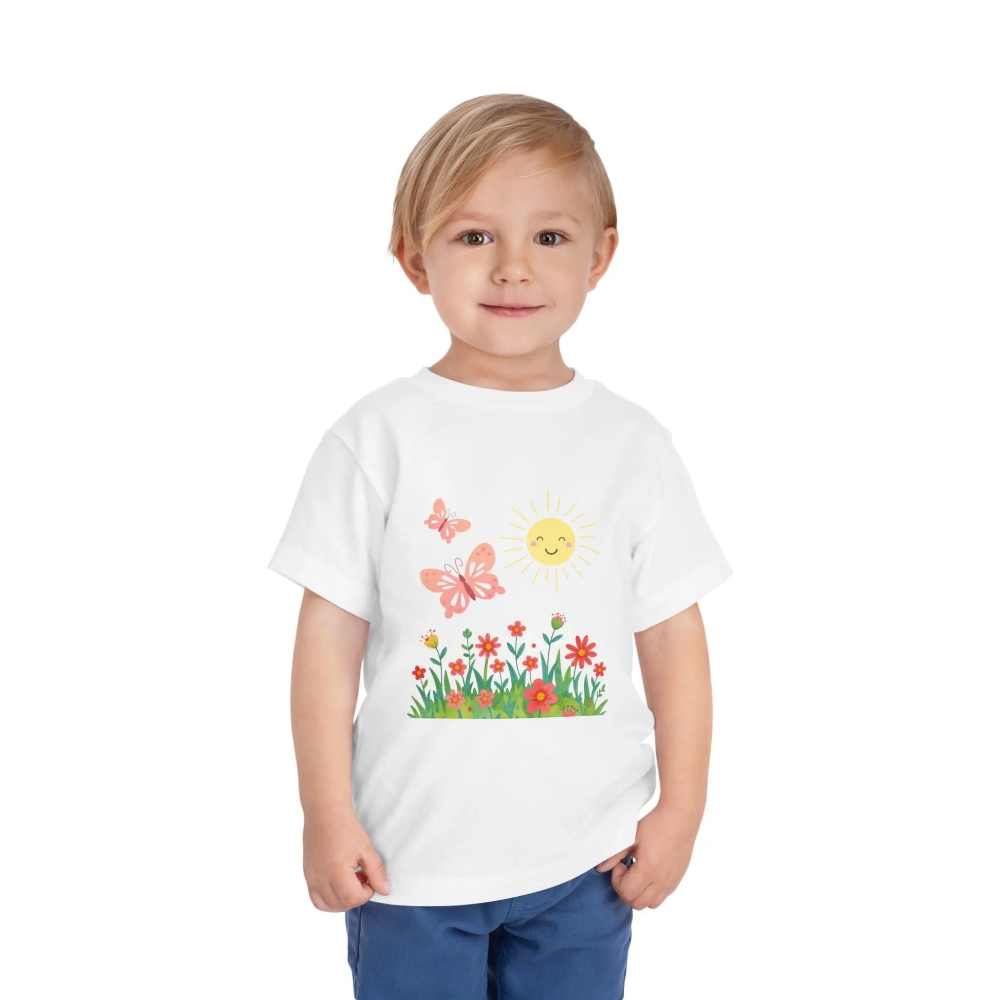 Toddler wearing a cheerful toddler tee with smiling sun, butterflies, and wildflowers. Soft cotton, perfect for spring, playdates, and outdoor adventures. Bright kids' clothing. White