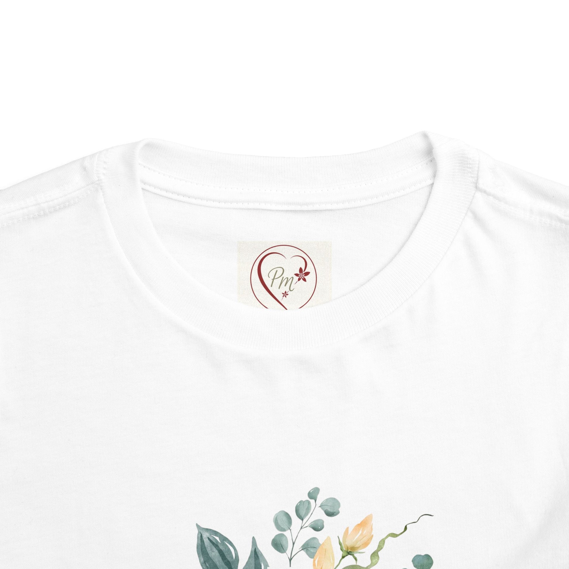 White t-shirt with floral design and a PM Creations 25 logo on a white background