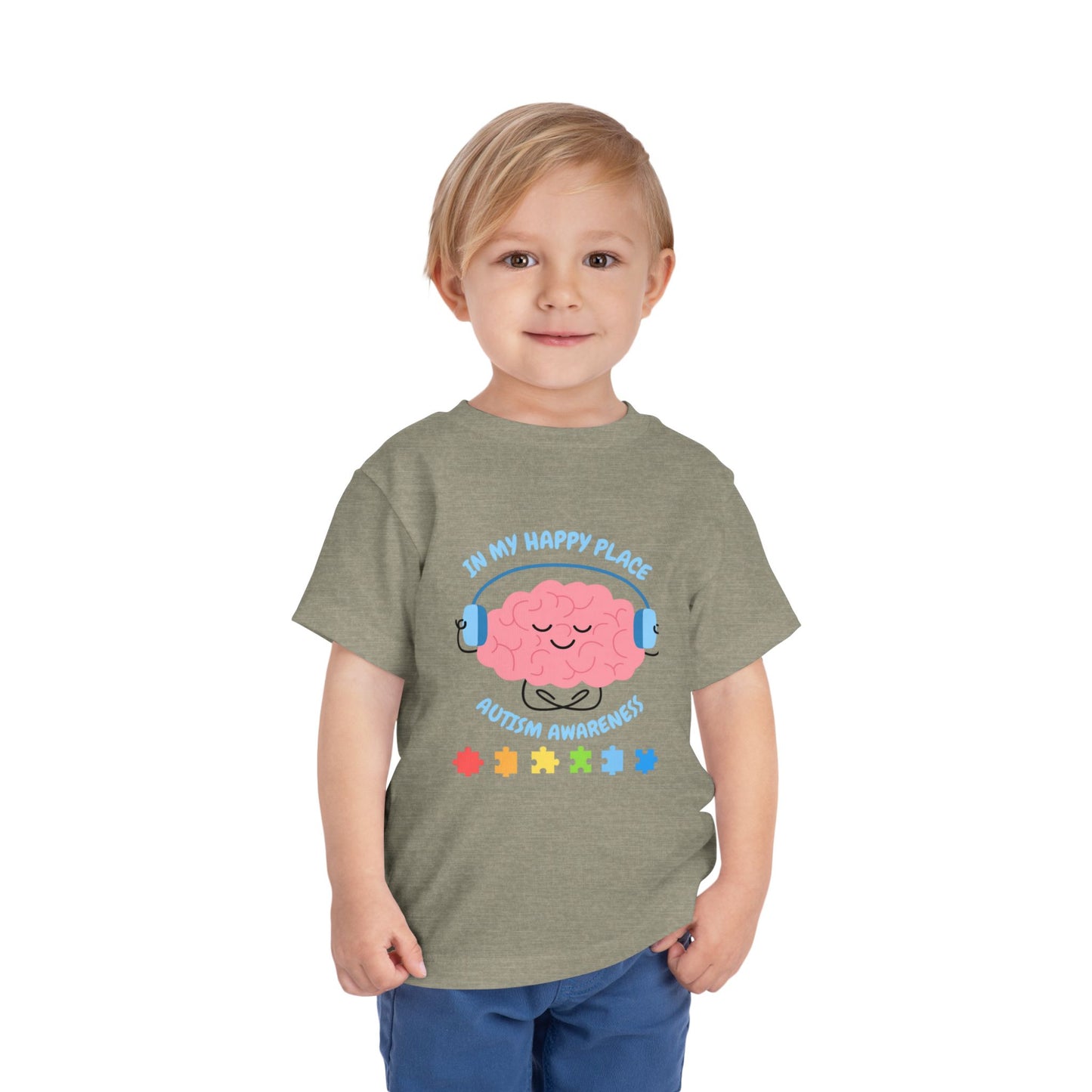 Child wearing a t-shirt with a colorful design on a white background. Shop our comfortable Toddler Tee featuring "In My Happy Place" autism awareness design, perfect for preschool and toddler kids. Heather Stone