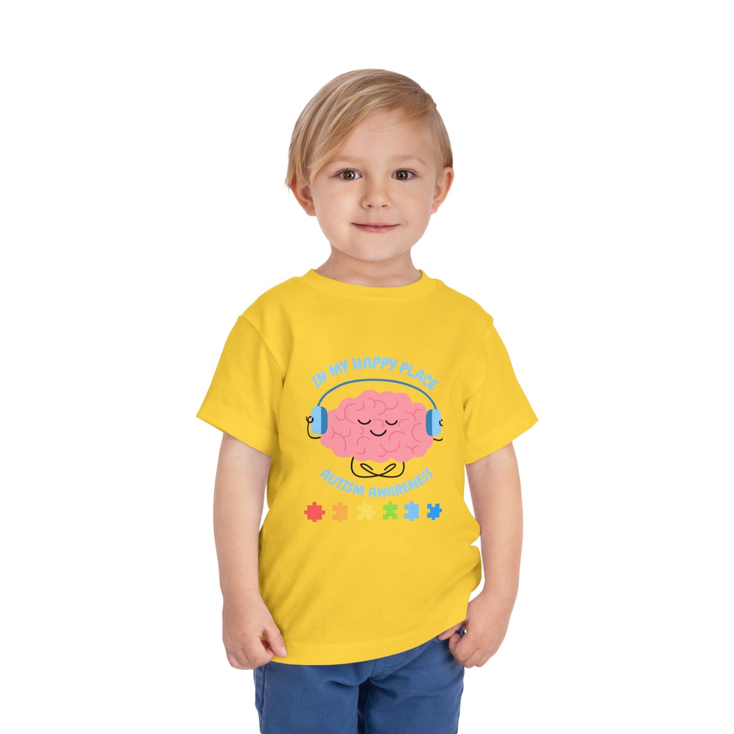 Child wearing a yellow t-shirt with a brain graphic and text on a white background. Shop our comfortable Toddler Tee featuring "In My Happy Place" autism awareness design, perfect for preschool and toddler kids. Yellow