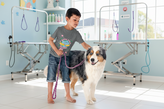 Toddler wearing Save Our Planet tee with smiling Earth in hands and flowers while holding a dog on a leash against a white background, Asphalt