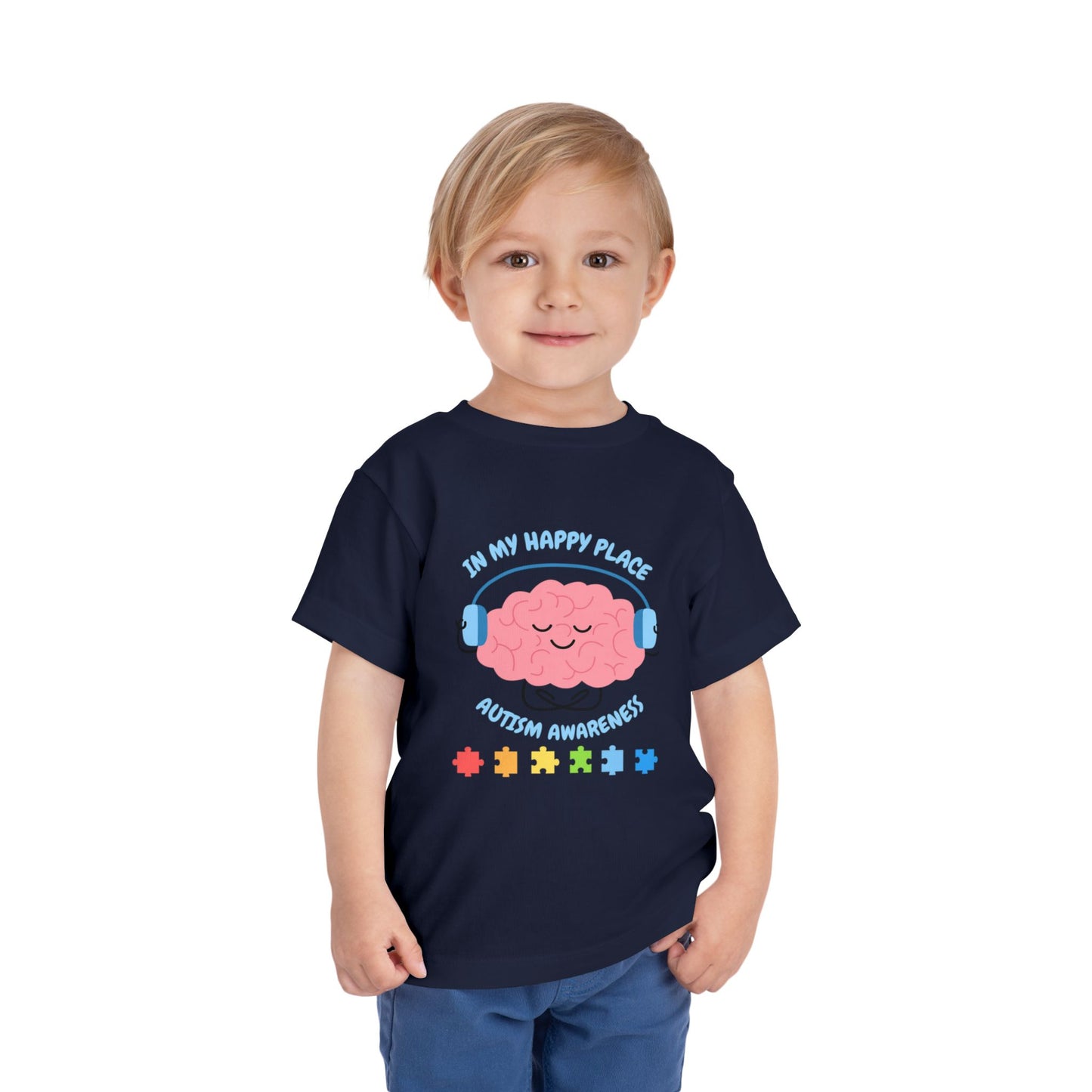 Child wearing a navy blue t-shirt with autism awareness design on a white background. Shop our comfortable Toddler Tee featuring "In My Happy Place" autism awareness design, perfect for preschool and toddler kids. Black