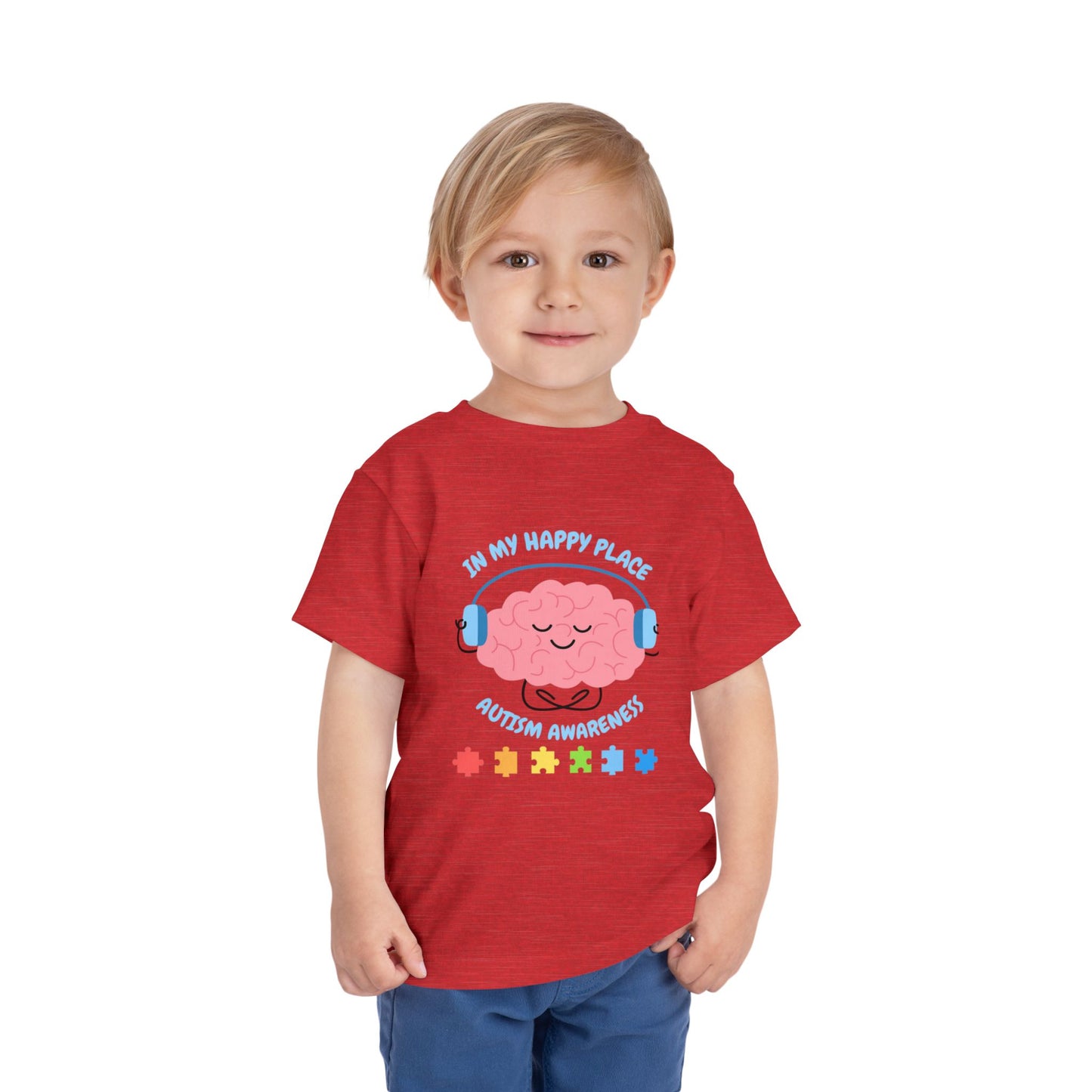 Child wearing a red t-shirt with autism awareness design on a white background. Shop our comfortable Toddler Tee featuring "In My Happy Place" autism awareness design, perfect for preschool and toddler kids. Heather Red
