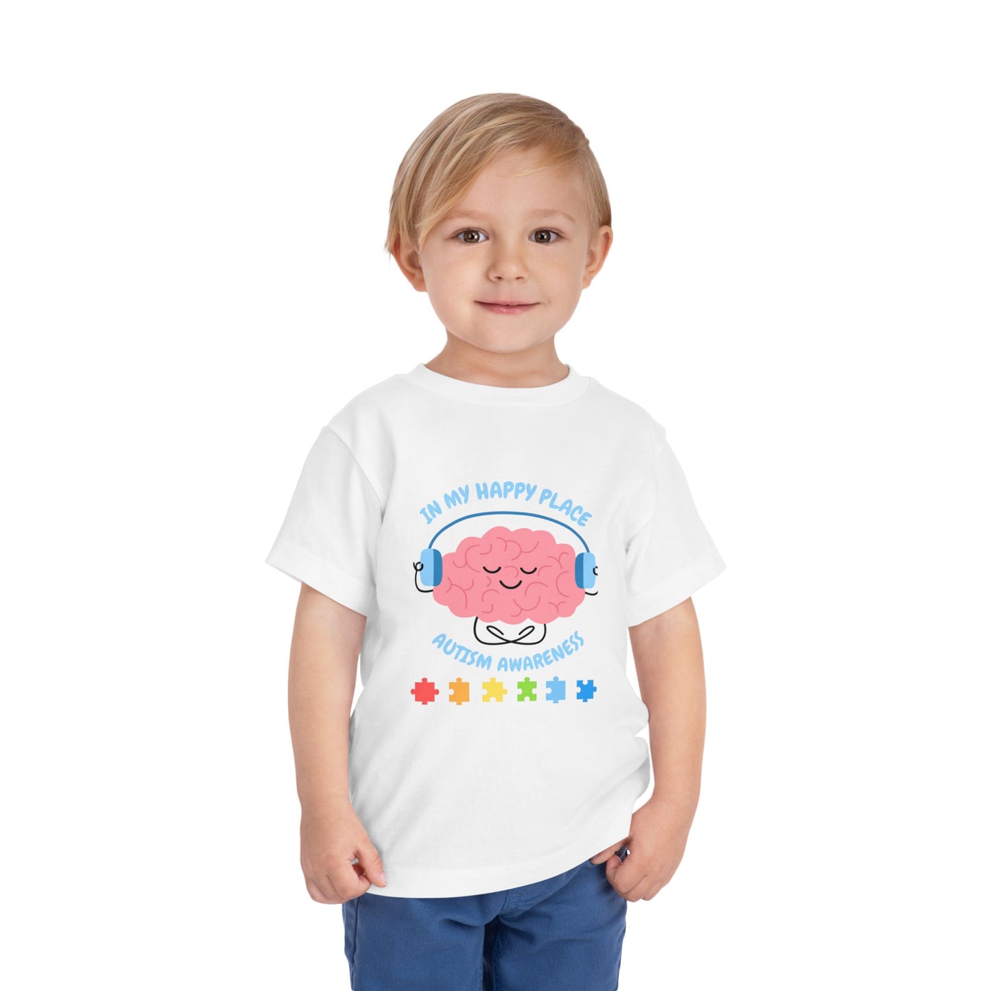 Child wearing a white t-shirt with a colorful design on a white background. Shop our comfortable Toddler Tee featuring "In My Happy Place" autism awareness design, perfect for preschool and toddler kids. White