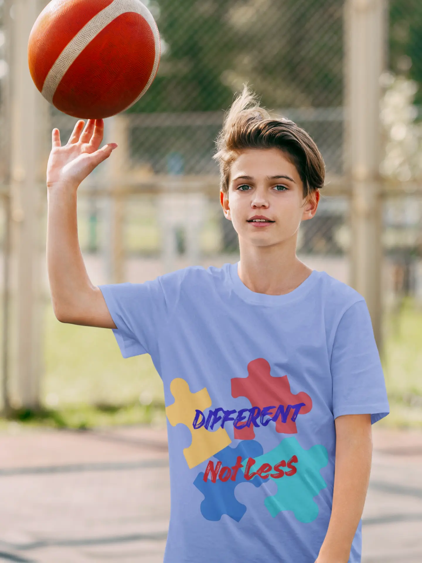 Youth wearing Different Not Less tee with colorful autism puzzle pieces, Heather Columbia Blue

