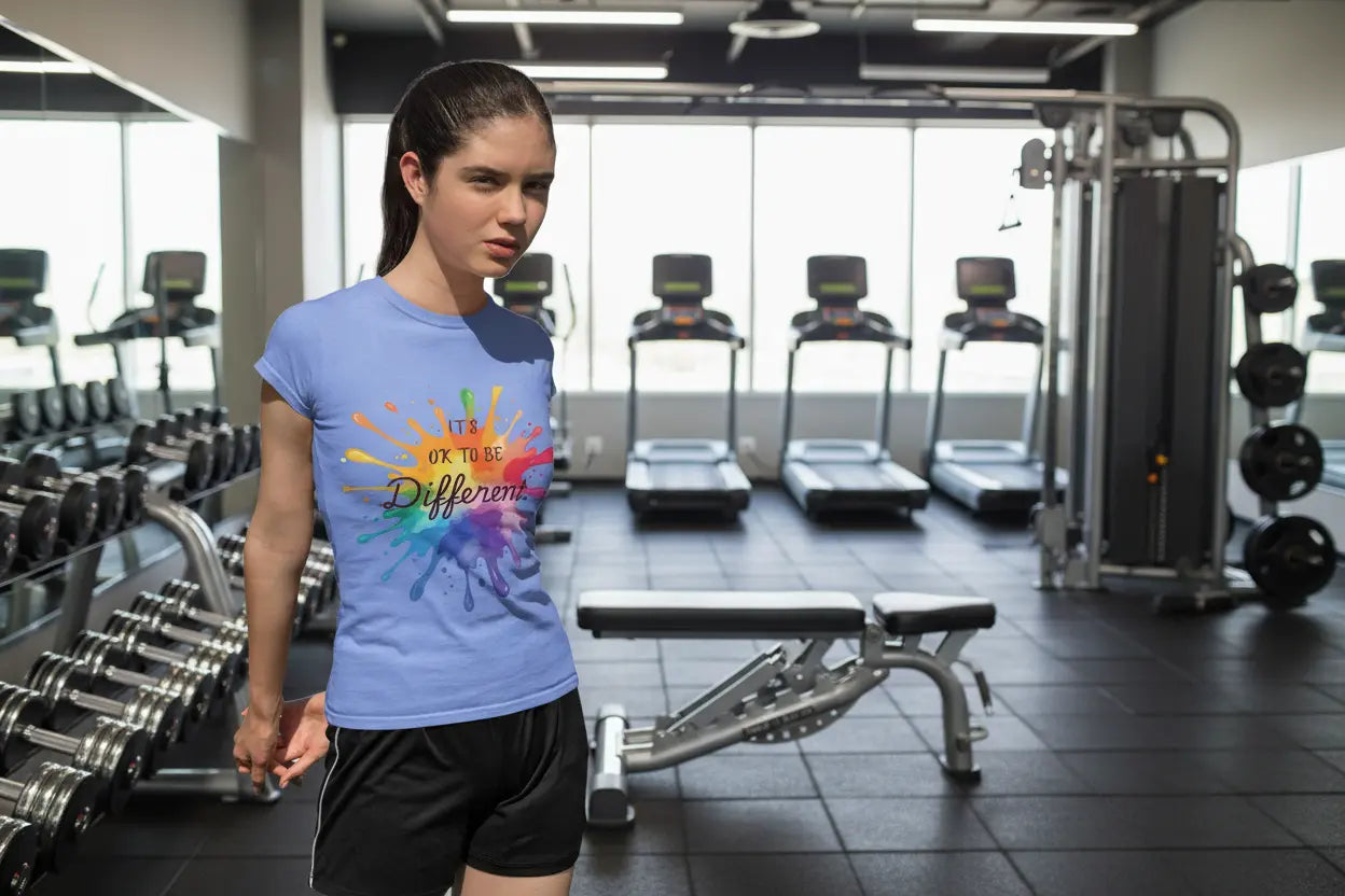 Youth wearing Columbia Heather Blue Bella Canvas shirt with rainbow paint splash design reading It's OK To Be Different, autism awareness tee by PM Creations 25